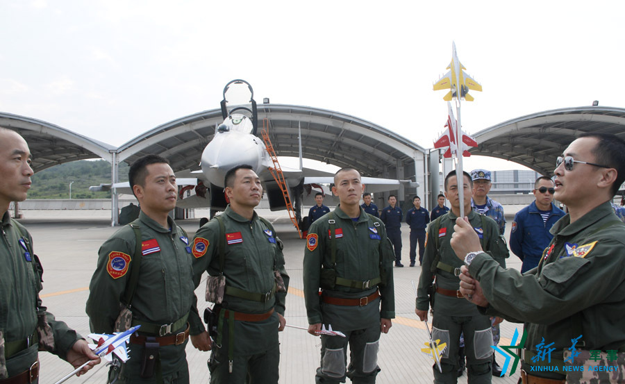 ↑艦載航空兵某部司令員戴明盟向飛行員演示空中飛行注意事項(xiàng)。